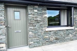 a stone house with a door and a window at Aghadoe Millers - Modern 3 bed house Killarney in Fossa