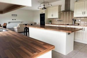 a kitchen with white cabinets and a wooden counter top at Aghadoe Millers - Modern 3 bed house Killarney in Fossa