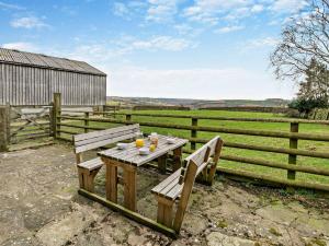 a wooden table with two benches next to a fence at 2 Bed in Wolsingham 94197 in Wolsingham