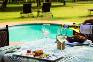 a table with a bottle of wine and a plate of food at Falaza Game Park and Spa in Hluhluwe