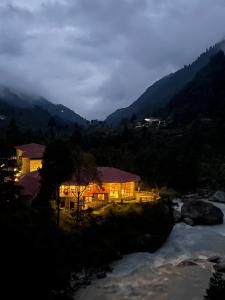 a house with lights on next to a river at Mountain Lodges of Nepal - Phakding in Phakding
