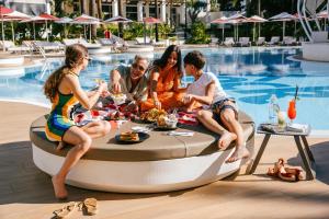 un grupo de personas sentadas en una bañera de hidromasaje junto a una piscina en Hard Rock Hotel Marbella - Puerto Banús, en Marbella