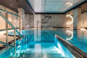 a swimming pool with blue water in a building at Deo Plaza Riverside & Radisson SPA by Downtown Apartments in Gdańsk