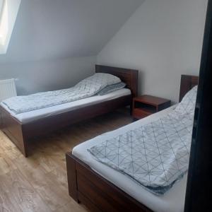 two twin beds in a room with two tables at Pensjonat Magnolia in Przejma Wielka