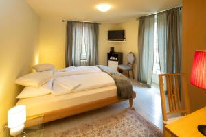 Dormitorio con cama, escritorio y TV en Locanda Villa d' Epoca en Aurigeno