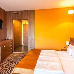 佩奇的住宿－Sándor Hotel，一间卧室设有一张床和黄色的墙壁
