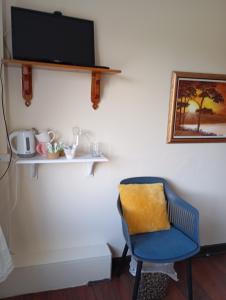 a room with a blue chair and a television on a wall at Room in Apartment - 1 Bedroom In A Homely Home With A Lovely Farm 