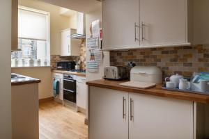 uma cozinha com armários brancos e uma bancada em Puffin View em Llanfairfechan