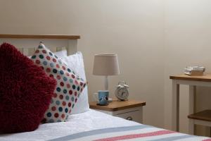 a bedroom with a bed with pillows and a clock at Puffin View in Llanfairfechan