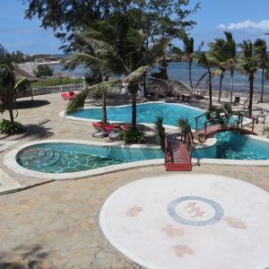 een zwembad van het resort met palmbomen en de oceaan bij Lily Palm Resort in Watamu