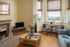 a living room with a blue couch and a table at Orme View in Llanfairfechan