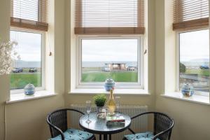 una mesa y sillas en una habitación con ventanas en Orme View en Llanfairfechan