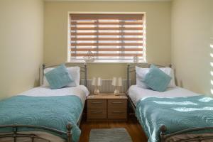two twin beds in a room with a window at Orme View in Llanfairfechan