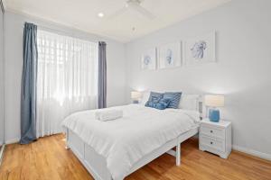 a white bedroom with a large bed and a window at NEW Sailors Cove Pet Friendly in Gosford