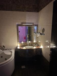 baño con bañera y lavabo con ventana en Samaa Eva Resort en Abha