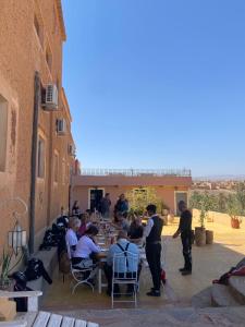 un groupe de personnes assises à une table dans un patio dans l'établissement Auberge Kasbah Ennakhile, à Nkob