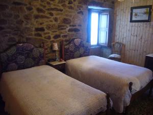 2 Betten in einem Zimmer mit einer Steinmauer in der Unterkunft Casa do Monge in Leomil