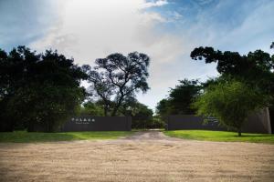 een onverharde weg met een hek en wat bomen bij Falaza Game Park and Spa in Hluhluwe