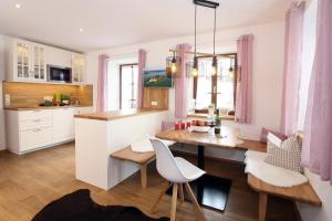 uma cozinha com uma mesa de jantar e uma cozinha com cortinas cor-de-rosa em Zellnerhof em Gstadt am Chiemsee