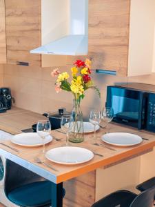 a table with glasses and flowers in a vase at Grand Studio in Le Blanc-Mesnil