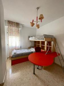 Magnífico Apartamento en Sevilla في إشبيلية: غرفة نوم مع طاولة حمراء وسرير بطابقين