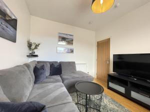 a living room with a gray couch and a flat screen tv at Skiddaw View in Keswick