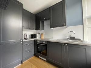 a kitchen with black cabinets and a sink at Skiddaw View in Keswick