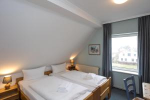 ヒデンゼーにあるHotel GODEWINDのベッド2台と窓のある寝室 +11枚の写真