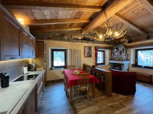 una cucina con tavolo rosso e una sala da pranzo di Chalet Chez Louis vista Catena Monte Bianco sulle piste da sci a Courmayeur