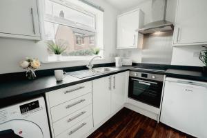 a kitchen with white cabinets and black counter tops at Sophisticated 2BR retreat for Contractors in charming Hinckley in Hinckley