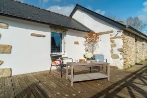 una terraza de madera con mesa y un edificio en Killiouarn - Charmante maison à 15min des plages, en Gouesnach
