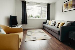 ein Wohnzimmer mit einem Sofa und einem TV in der Unterkunft Sophisticated 2BR retreat for Contractors in charming Hinckley in Hinckley