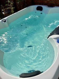 a bath tub filled with blue water in at “Hot Tub, Private Parking, Beachside Luxury” in Cleethorpes