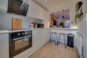 a kitchen with white cabinets and two bar stools at “Hot Tub, Private Parking, Beachside Luxury” in Cleethorpes