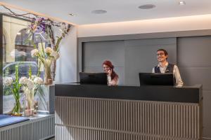 a man and a woman standing at a reception desk at The Resident Covent Garden in London