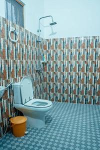 a bathroom with a toilet and a tiled wall at Digital nomad Cave- Zanzibar in Stone Town