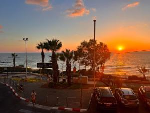 a sunset over the ocean with cars parked in a parking lot at Elis Boutique Hotel in Bat Yam