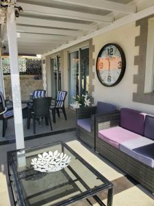 een veranda met een bank en een klok aan de muur bij Villa Sunrise with heated pool. in Callao Salvaje