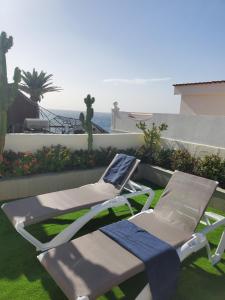 a pair of lounge chairs and a laptop sitting on a lawn at Villa Sunrise with heated pool. in Callao Salvaje