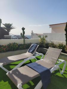 two lounge chairs and a towel sitting on the grass at Villa Sunrise with heated pool. in Callao Salvaje
