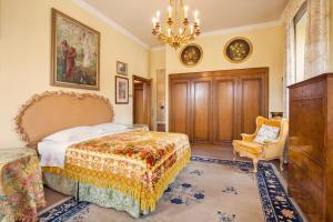 een slaapkamer met een bed, een stoel en een kroonluchter bij Villa Lidia-Dimora storica a Caprino Veronese in Caprino Veronese