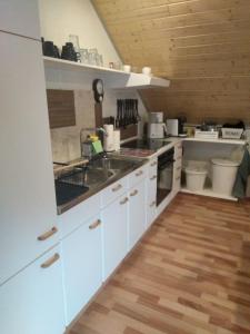 cocina con armarios blancos y suelo de madera en Ferienwohnung Monteurwohnung Pusteblume, en Duderstadt
