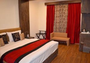 a bedroom with a large bed and red curtains at Hotel Green Leaf , Srinagar in Srinagar