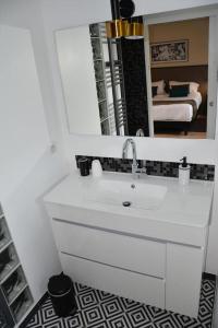 a bathroom with a white sink and a mirror at Le clos de la lande vallée in Bringal