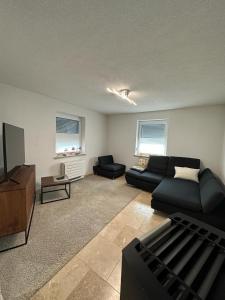 a living room with a black couch and a tv at Ferienhaus Federico nahe Legoland in Burgau