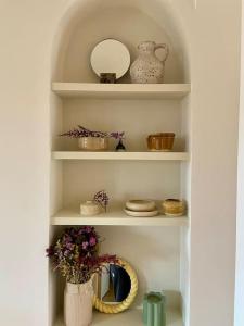 a white shelf with dishes and a vase with flowers at Appartement familial, vue canal Ourcq, parking in Pantin