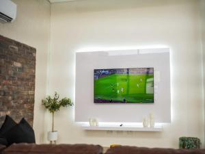 uma sala de estar com uma televisão na parede em The Lofts Prestige Suites em Windhoek