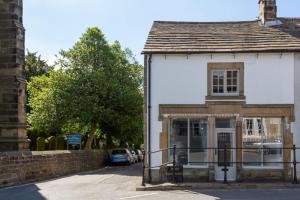 a white building with a gate in front of a street at Beautifully Renovated Old Sweet Shop in Youlgreave