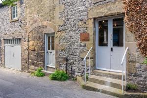 a stone building with a white door and stairs at Beautifully Renovated Old Sweet Shop in Youlgreave
