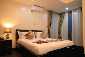 een slaapkamer met een groot bed met kussens bij Precious Villas Lubowa in Kampala